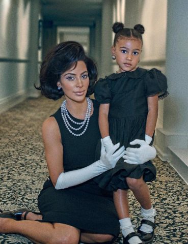 Kim Kardashian wearing a triple-strand pearl necklace and pearl earrings, with North West wearing big pearl earrings too.