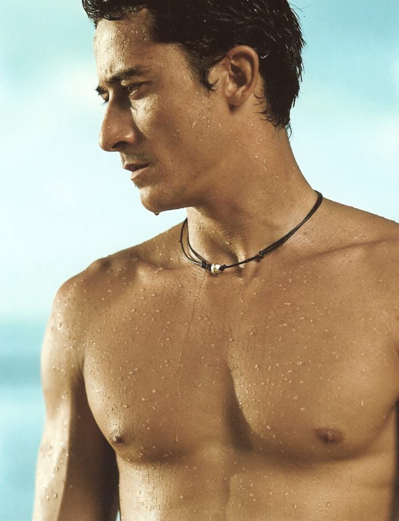 As he stands in the sunlight staring at the blue sea... wearing a leather necklace with a single pearl...