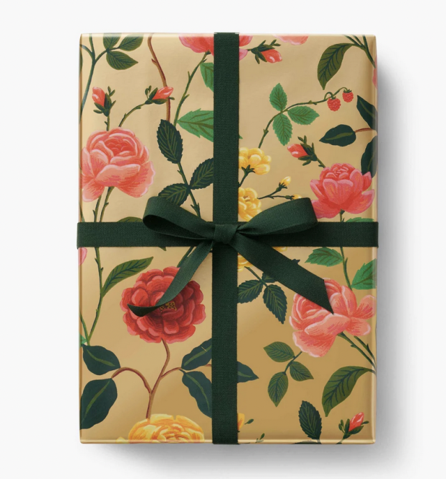 Luxury wrapping paper with a gold base, painted flowers, and a green ribbon.