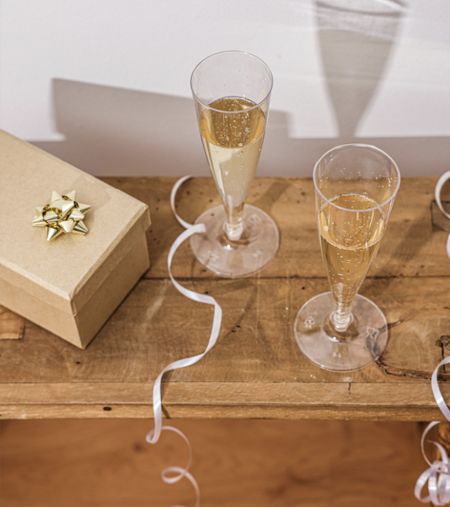 Two glasses of champagne on a table with a gift.