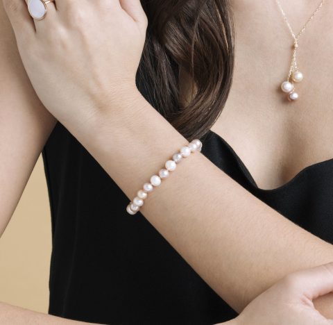 A close up shot of a woman wearing a stylish freshwater pearl bracelet, with variation of pink pearl tones.