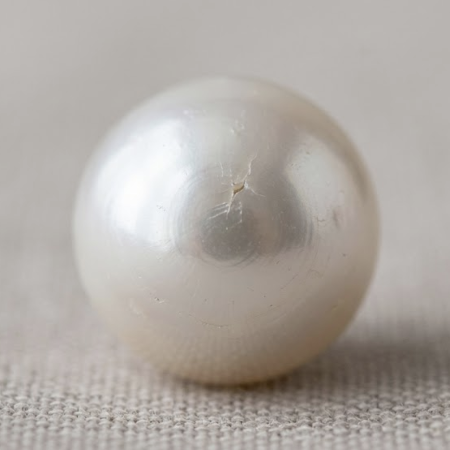 A small crack appears on a pearl that has been dropped.