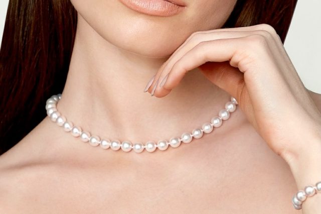 Close-up of a woman wearing a white pearl choker necklace.