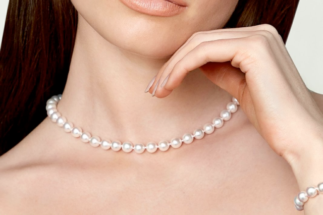 Close-up of a woman wearing a white pearl choker necklace.