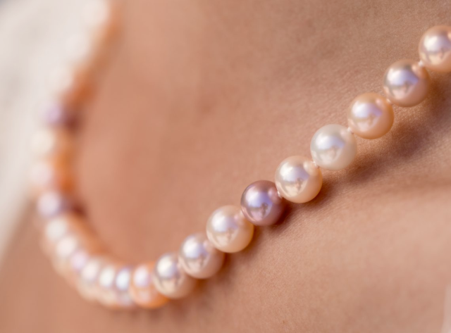 Close-up of a lavender pearl necklace worn on the collarbone, showing soft pink and silver overtones.