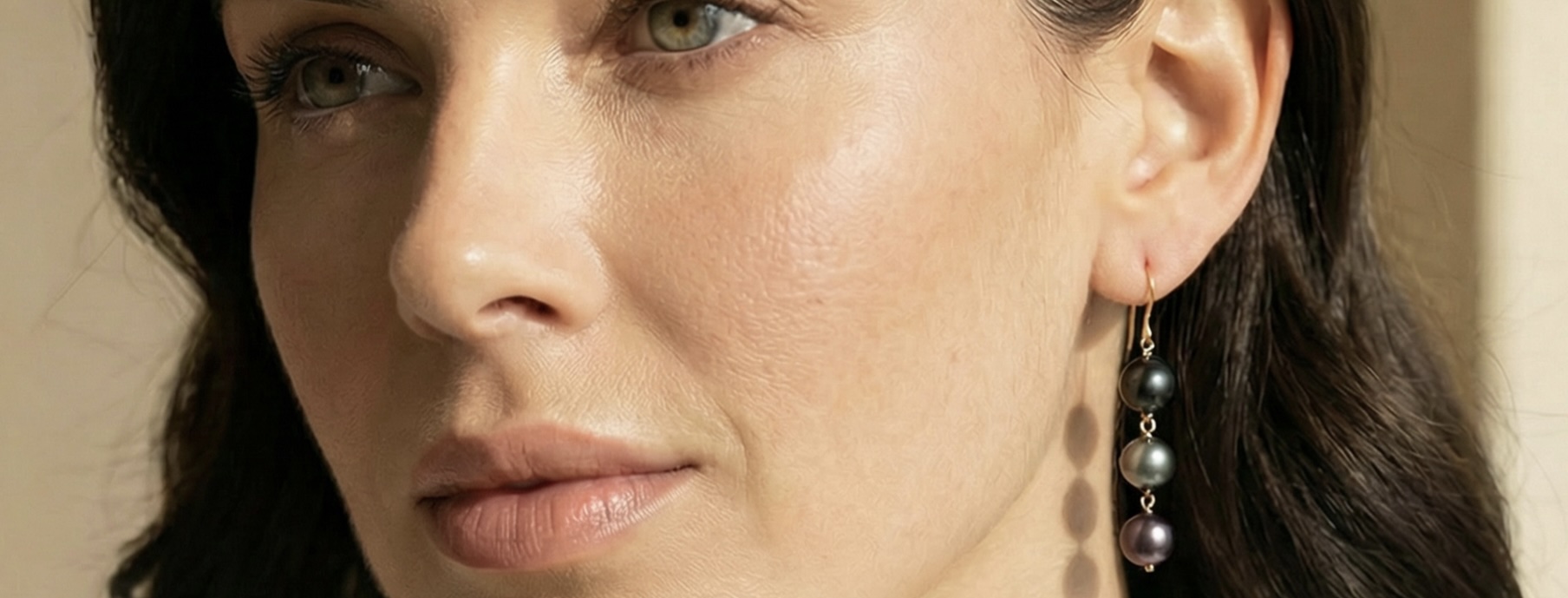 Closeup image of a woman wearing multicolor Tahitian pearl tincup earrings.