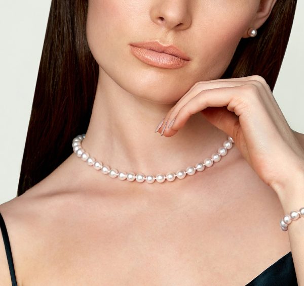 Woman wearing a classic strand of white Akoya pearls, complete with matching studs and bracelet.